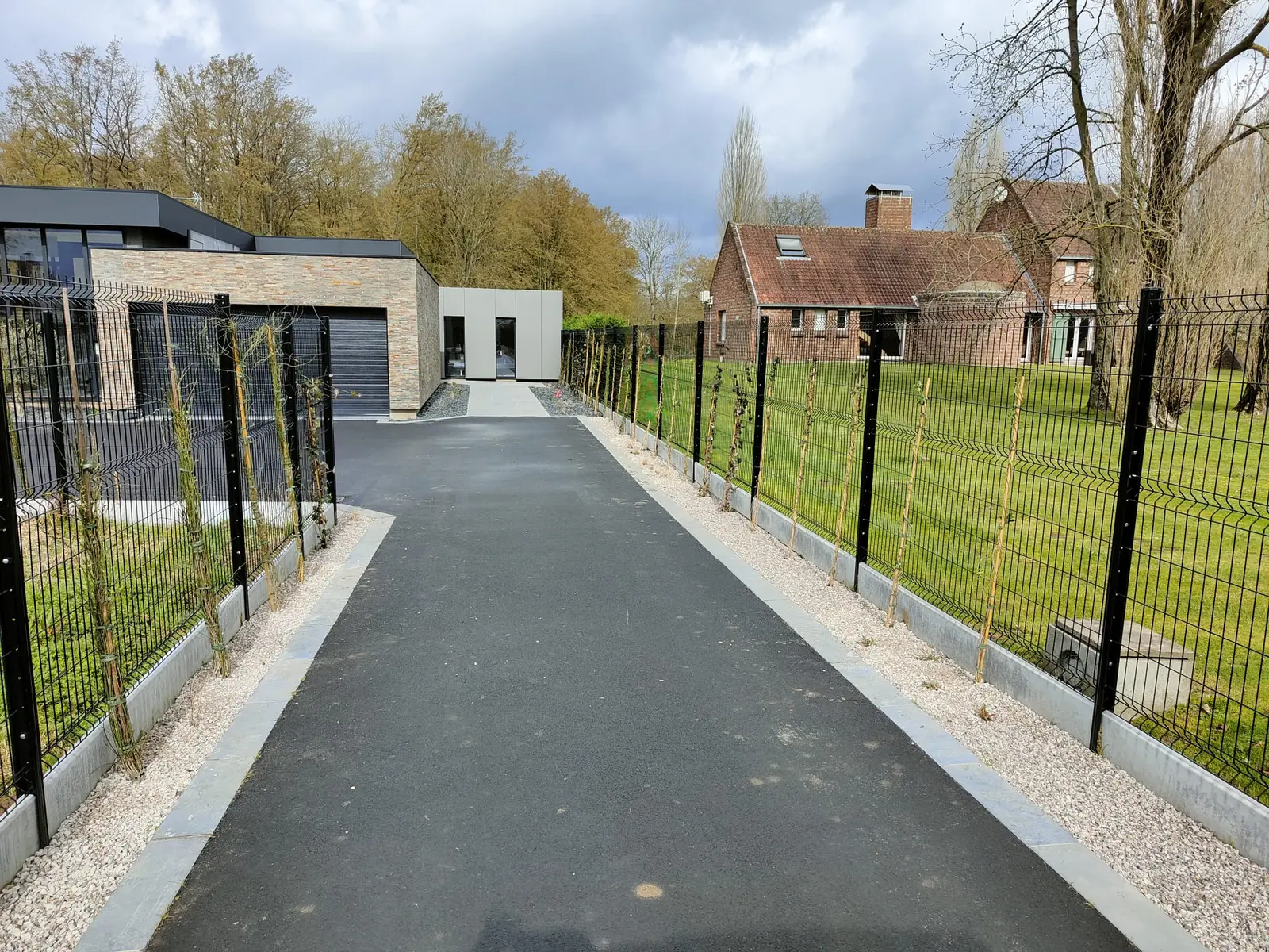 Allée de maison en enrobé bordée de graviers
